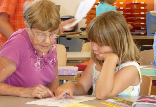 Seniorin unterstützt Schülerin innerhalb der Klasse